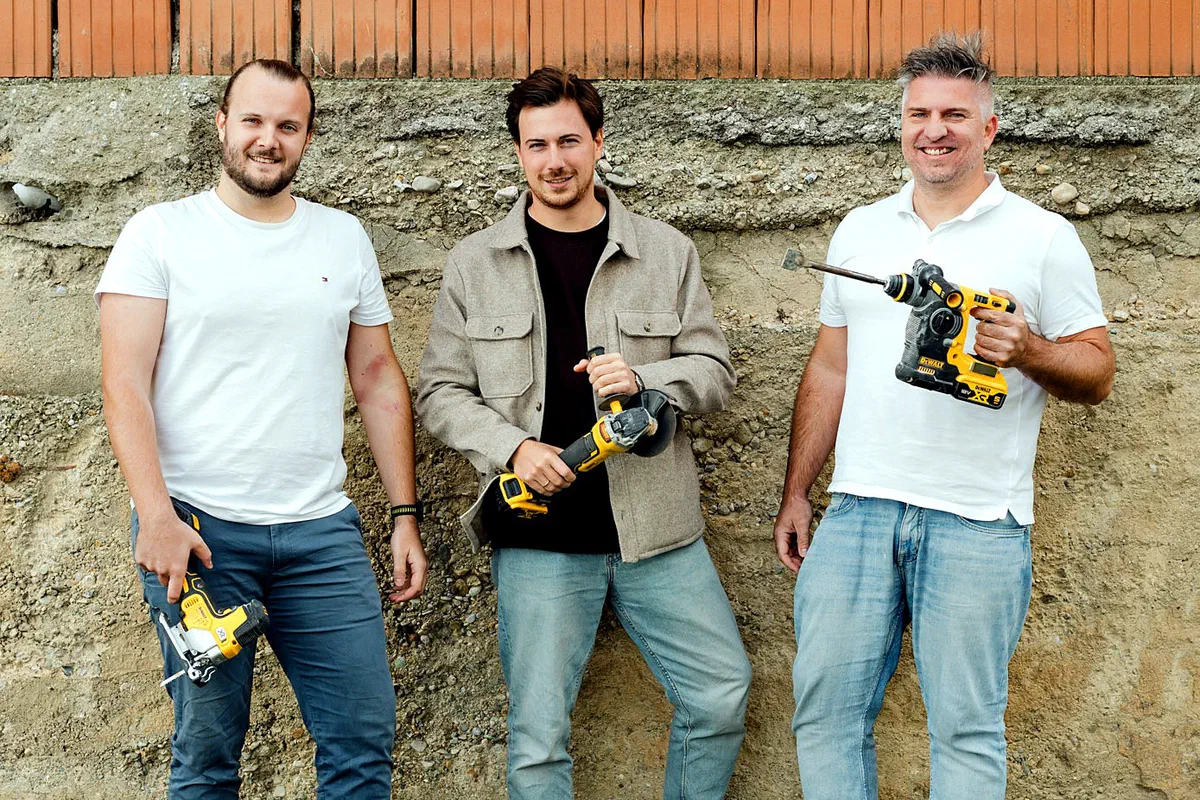 Christoph Harrison, Pascal Giefing und Tommi Schmid stehen vor einer Ziegelmauer, jeder mit einem Akku-Werkzeug in der Hand